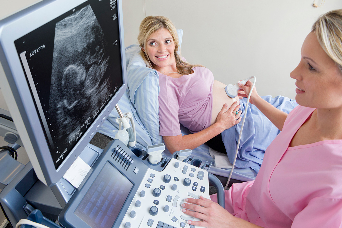 Practitioner performing ultrasound on pregnant IVF patient